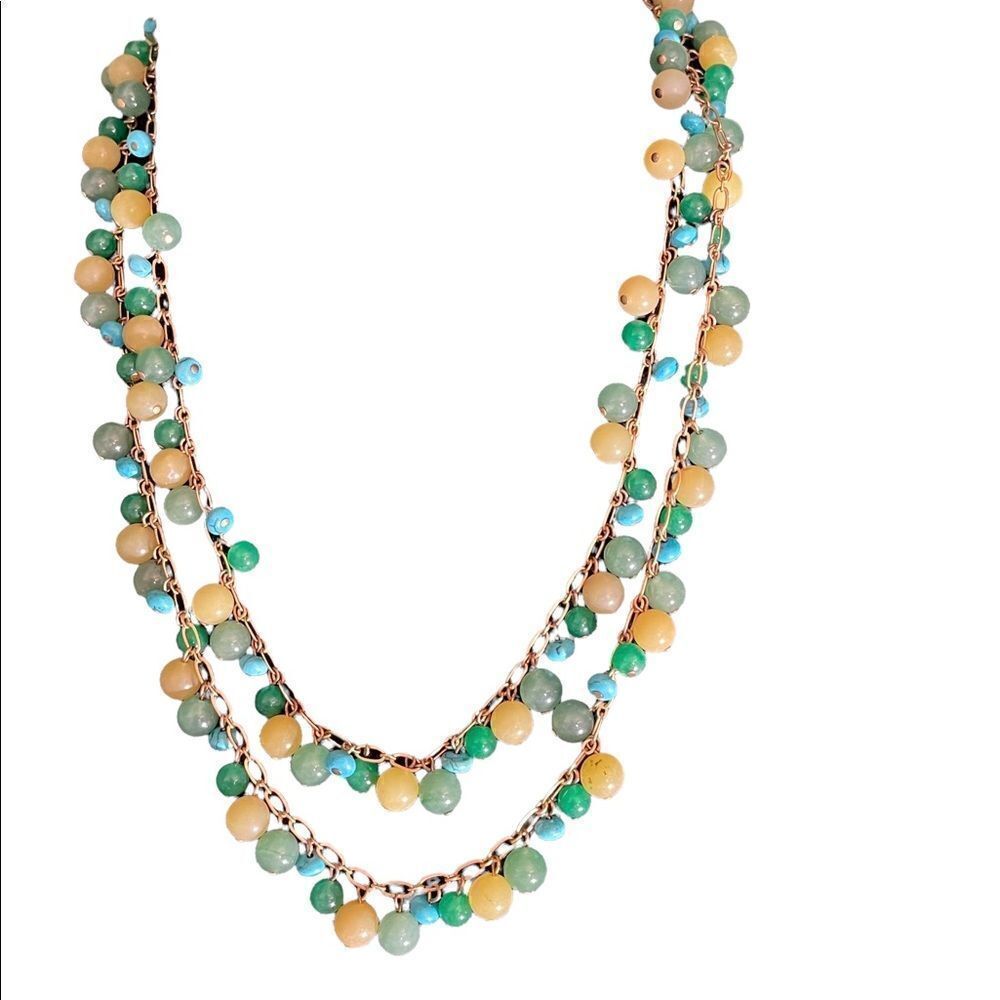 Long gold tone hardware necklace with green, yellow and turquoise beads.